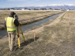 Boundary surveying beside an irrigation canal crossing a property lot in Herriman Utah
